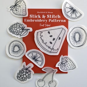 May include: A set of 10 iron-on embroidery patterns featuring various fruits, including a watermelon, kiwi, strawberry, blackberry, and lemon. The patterns are printed on white fabric and are labelled "Stick & Stitch Embroidery Patterns" and "Fruit Salad".