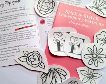 May include: A set of embroidery patterns featuring floral designs and letters. The patterns are printed on white fabric and are ready to be stitched. The patterns are titled "Stick & Stitch Embroidery Patterns Monogram Blooms".