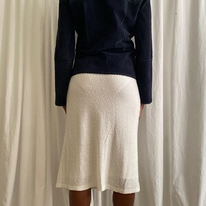 K&ouml;nnte beinhalten: Marineblaue Wildlederjacke mit sichtbaren Steppn&auml;hten, kombiniert mit einem wei&szlig;en, strukturierten knielangen Rock. Die Jacke hat lange &Auml;rmel und eine taillierte Passform. Der Rock hat eine leichte A-Linien-Form.