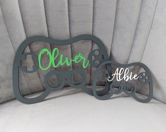 May include: Two black wooden game controller shapes with the names "Oliver" in green and "Albie" in white.