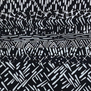 May include: Black and white fabric with a variety of geometric patterns. The fabric is made up of several strips of different patterns, including dots, stripes, and zigzags.