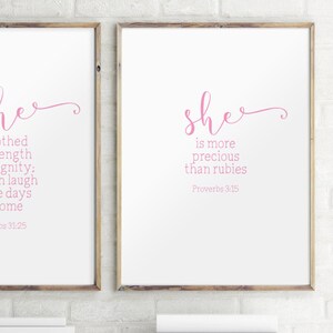 Peut inclure: Deux impressions encadr&eacute;es avec du texte rose sur fond blanc. L'impression de gauche dit "Elle est v&ecirc;tue de force et de dignit&eacute;&nbsp;: elle rit des jours &agrave; venir. Proverbes 31&nbsp;:25". L'impression de droite dit "Elle est plus pr&eacute;cieuse que les rubis. Proverbes 3&nbsp;:15".