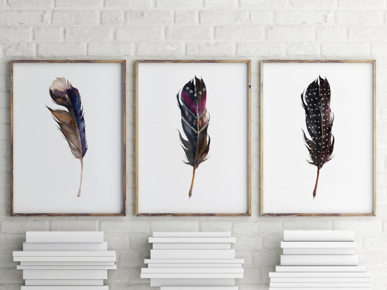 May include: Three framed watercolor paintings of feathers. The feathers are in shades of brown, black, purple, and white. The feathers are arranged in a vertical orientation.