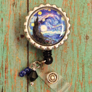 May include: A silver badge reel with a clear plastic badge holder and a black and silver charm. The charm features a blue and yellow image of Vincent van Gogh's Starry Night.