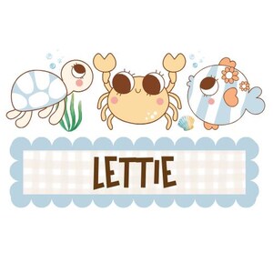 May include: A charming illustration of a turtle, crab, and fish with big eyes. The crab is light orange, the turtle has a white shell with blue accents, and the fish is striped. The name "LETTIE" is displayed in brown letters on a blue scalloped banner.