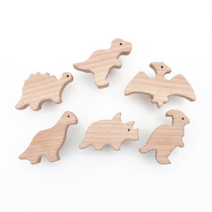 May include: Set of six wooden dinosaur toys, including a stegosaurus, triceratops, pterodactyl, and three different types of dinosaurs. The toys are all made of natural wood and are unpainted.