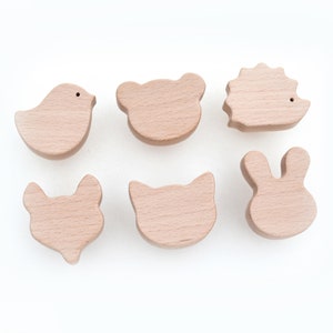 May include: Six wooden animal shapes, including a bird, bear, hedgehog, rabbit, cat, and fox. The shapes are all light brown and have a smooth, unfinished surface.