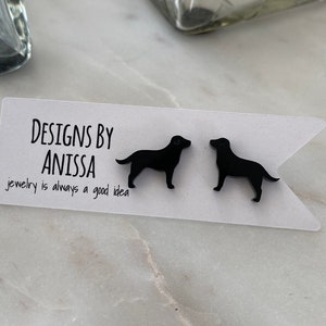 May include: Black dog-shaped earrings on a white card with the text "DESIGNS BY ANISSA" and "jewelry is always a good idea". The earrings are displayed on a white surface.