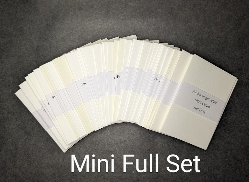 May include: A fan of off-white paper sheets, each with a label. The text "Arches Bright White 100% Cotton Hot Press" is visible on one label. The words "Mini Full Set" are at the bottom. The background is dark gray.