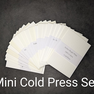 Puede incluir: Un abanico de muestras de papel de prensa en fr&iacute;o blanquecino, etiquetadas. El conjunto incluye papel Arches Bright White 100% Cotton Cold Press. Las palabras "Mini Cold Press Set" est&aacute;n en la parte inferior de la imagen.
