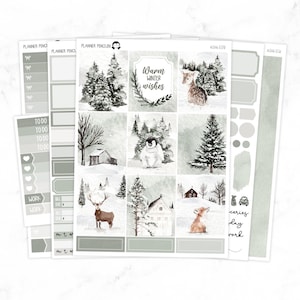 Op de afbeelding: Een set winterse planner stickers met een pinguïn, hert, vos en bomen. De stickers zijn op een witte achtergrond met een lichtgrijze rand. De tekst "Warm Winter Wishes" is op een van de stickers opgenomen.