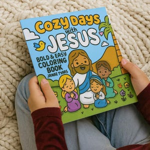 K&ouml;nnte beinhalten: Ein Kind h&auml;lt ein Malbuch mit dem Titel "Cozy Days with Jesus". Das Cover zeigt eine Cartoon-Illustration von Jesus mit Kindern, vor blauem Himmel und gr&uuml;nem Gras. Das Buch tr&auml;gt den Titel "Bold & Easy Coloring Book" von Janae Tyars.