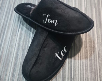 May include: A pair of black slippers with the names "Tom" and "Tee" embroidered on them in white.