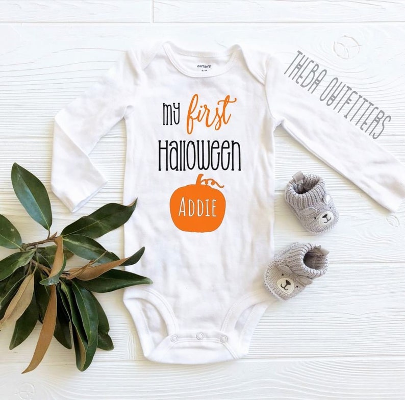 May include: White long-sleeve baby onesie with the text "my first Halloween" and a pumpkin with the name "Addie" printed on it.