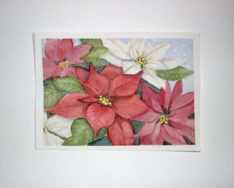 Original watercolor painting on textured acid free paper of red, white and pink poinsettia flowers. This colorful floral picture was painted in a 5x7 inch horizontal format. Touches of green leaves are interspersed between the flowers. Holiday theme.