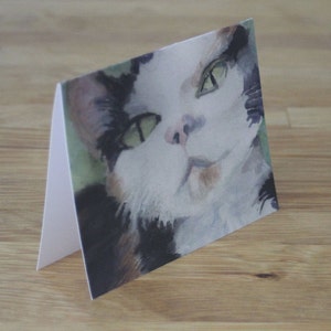 May include: A watercolor painting of a cat with green eyes and a white, black, and orange coat. The cat is looking directly at the viewer.
