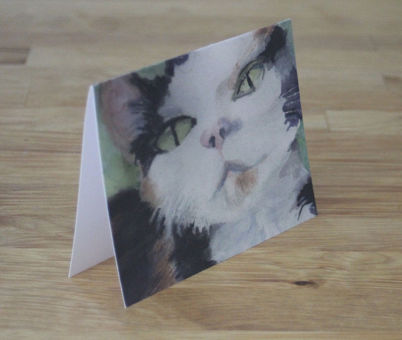 May include: A watercolor painting of a cat with green eyes and a white, black, and orange coat. The cat is looking directly at the viewer.