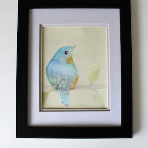 K&ouml;nnte beinhalten: Ein gerahmtes Aquarellbild eines blauen Vogels, der auf einem Zweig mit gr&uuml;nen Bl&auml;ttern sitzt. Der Vogel schaut nach rechts und hat eine gelbe Brust. Das Bild ist vor einem hellgelben Hintergrund gemalt.