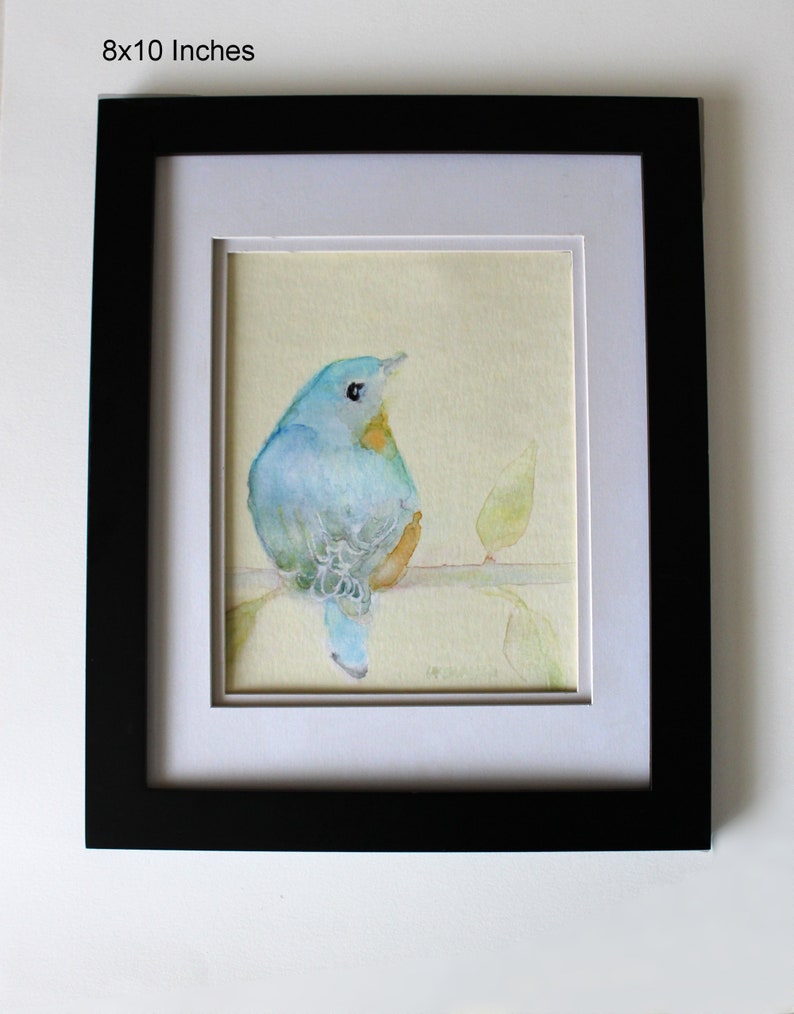 K&ouml;nnte beinhalten: Ein gerahmtes Aquarellbild eines blauen Vogels, der auf einem Zweig mit gr&uuml;nen Bl&auml;ttern sitzt. Der Vogel schaut nach rechts und hat eine gelbe Brust. Das Bild ist vor einem hellgelben Hintergrund gemalt.