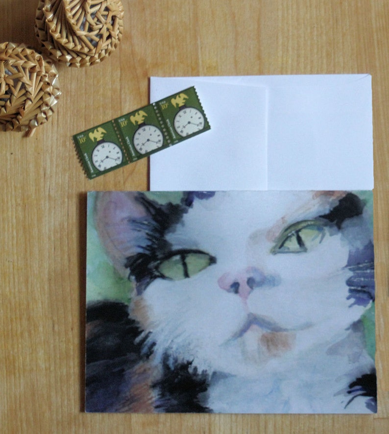 May include: A watercolor painting of a cat's face. The cat has black, white, and brown fur. The cat's eyes are green and the cat is looking directly at the viewer.