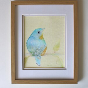 K&ouml;nnte beinhalten: Ein gerahmtes Aquarellbild eines blauen Vogels, der auf einem Zweig mit gr&uuml;nen Bl&auml;ttern sitzt. Das Bild ist vor einem gelben Hintergrund platziert und in einem hellen Holzrahmen gerahmt. Der Rahmen ist 20,32 x 25,4 cm gro&szlig;.