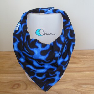 May include: A blue and black bandana with a flame pattern. The bandana is folded in a triangle shape. The bandana is made of fabric and has a tag on the side.