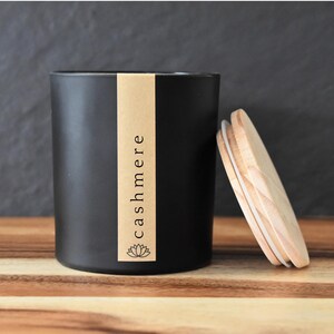 May include: Black candle jar with a brown label that says "cashmere". The jar has a wooden lid.