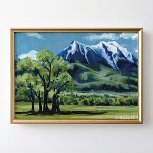 May include: A painting of a mountain range with snow-capped peaks, green hills, and a group of trees in the foreground. The sky is blue with white clouds. The painting is framed in gold.