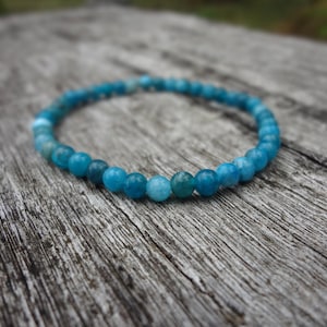 May include: A blue gemstone bracelet with round beads. The bracelet is made of natural stones and is a beautiful shade of blue.