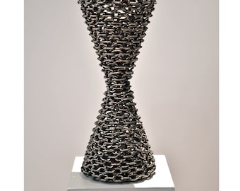 May include: A large, silver, hourglass-shaped sculpture made entirely of linked metal chains.