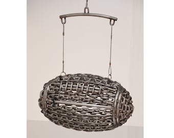 May include: A silver metal sculpture of a football made of chains, hanging from a metal bar.