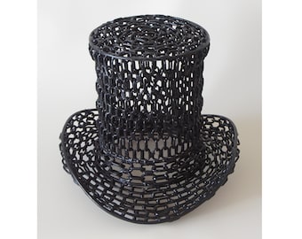 May include: A black metal hat sculpture made of linked chains. The hat is a tall top hat with a wide brim.