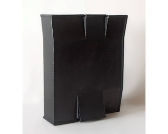 May include: A black ceramic sculpture with a geometric shape. The sculpture is made of multiple pieces that are joined together to create a unique form.