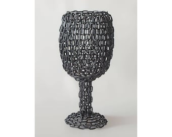 May include: A black metal wine glass sculpture made entirely of linked chains.
