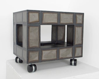 May include: A gray metal shelf unit with a rectangular shape and a single shelf. The shelf unit has four black wheels and is made of individual metal squares.