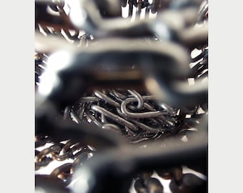 May include: A close-up view of a metal sculpture made of interlocking chains. The chains are arranged in a circular pattern, creating a sense of depth and texture.