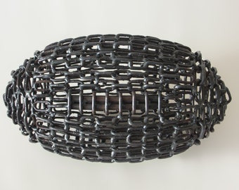 May include: A black metal sculpture of a football made from interlocking chains.