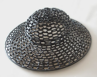 May include: A black, wide-brimmed hat made of woven metal chain links.