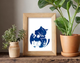 May include: A framed print of a blue silhouette of a cat curled up with flowers. The print is in a light wood frame and is sitting on a wooden shelf with two potted plants.