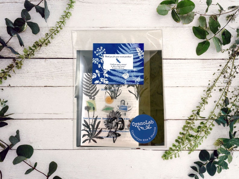 May include: A clear plastic bag containing a cyanotype kit with a blue and white floral design. The kit includes a thank you note that says "Thank you for your recent purchase! Could you spare a moment to leave a review? It would be a huge help!"
