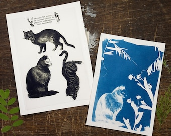 May include: Two cards with black and white illustrations of cats on a white background and a blue cyanotype print of a cat and plants on a white background. The text on the card reads "Découper les pochoirs et disposer-les sur le papier en combinant avec des plantes."