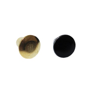 May include: Two metal rivets, one gold and one black, with a round head and a short cylindrical shank.