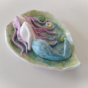 Sirena de cerámica sobre hoja: pelo lila y cola azul, decoración de fantasía.