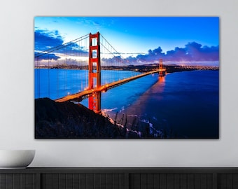 May include: A photograph of the Golden Gate Bridge in San Francisco, California. The bridge is lit up at night, and the water is a deep blue. The sky is a dark blue with clouds.