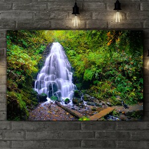 May include: A lush green forest scene with a cascading waterfall flowing over moss-covered rocks. The water is clear and blue, and the surrounding foliage is vibrant green.