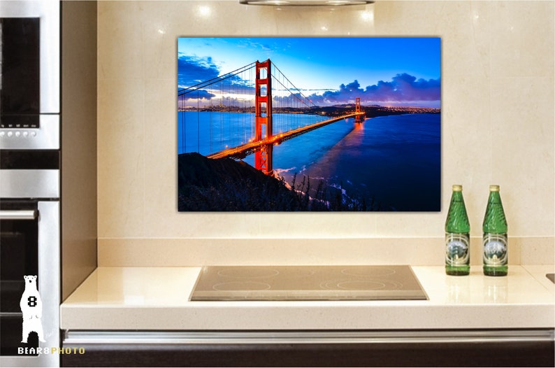 May include: A photograph of the Golden Gate Bridge in San Francisco, California. The bridge is lit up at night, and the water is dark blue. The sky is a deep blue with clouds.