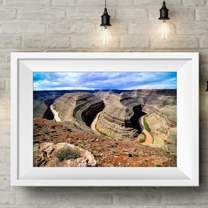 May include: A panoramic view of a winding river cutting through a canyon with layered rock formations. The sky is blue with white clouds.