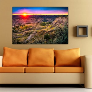 May include: A panoramic photograph of a canyon landscape with a vibrant sunset in the background. The sky is a mix of pink, orange, and blue hues, with the sun setting behind the canyon walls. The canyon is a rugged and rocky landscape, with a variety of vegetation growing on the slopes.