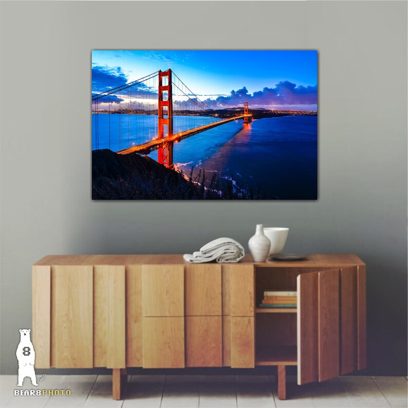 May include: A photograph of the Golden Gate Bridge in San Francisco, California. The bridge is lit up at night, with the city lights visible in the background. The sky is a deep blue with a few clouds.