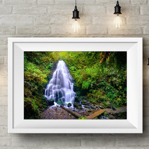 May include: A photograph of a waterfall cascading down a rocky cliff in a lush green forest. The water is flowing over moss-covered rocks and the surrounding foliage is vibrant.